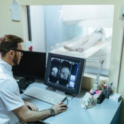 Doctor supervising brain scan procedure of a patient from control room.