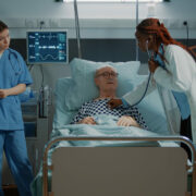 Multi ethnic personnel treats patient in hospital ward at medical clinic. Sick old man receiving modern treatment with nasal oxygen tube and IV drip bag from nurse and doctor at facility SSUCv3H4sIAAAAAAAACjxSy27bMBD8FYFn0+Wbom9tkjYoECCHAjnERbB8yBZMi4ZEpQiC/HtXyuMiLJezM5xZvRIPUx/I7pX0Oc9THaH2ZSA7tiFjGmIa1/J5lIatVYp9LWMPeT15qOE4wDmR3TDn/LYhU4U6T2lCRjwFqOmA8PX8KfX4uvTJjtwmyPUYYEzf7pA3ICkSzB6v7voppJxhSGWeyNvmc+RPQr2Sy+HlC3pVzpe5phFhfzcEDmkIL4s6yo8pJ1gf80haJzutgqEeoqKKd5oCfqngwjrrvbHKImfknQmKa6o1F1RF4RGWHGXRqo5z35nIEKajAqG8pTLKliplJXUGYW3Qtm29ScoJhEkItoNkqDbRU2VtQHmNlFGzBBK8sBxhiekkNEqZqBCmwFHfckWtNa3lHRhhOoLmTv/Q5/kjW5hjX5ZYnwsmh02JzcvYh344vCNKPS77w+zKPNQRUyEolku5gM+4sg7H0oYcYZoQED8ay9rwRyjnd5Kh1CXAZTLiNrHiUlijpDOW8VYYycyyi3Xvxx4HF6FlEstw6uPHc3vkJ8KLjnXS07ZVnCpjOHUqaorZCxmc1B3vkGy+5AKxLu5wsivjeV3+CBP6Xy2g4wvUIzZvdvs93zYPZTyh8eb+WGqZ9nsr3bb5edPclunSV8jNA4yxoc2PDOHUXJeA71wHr8uQ9vvvjIknplnLuXBPV7x1W8ac41bx7e/7X+TtPwAAAP//AwDcvEGwKQMAAA==